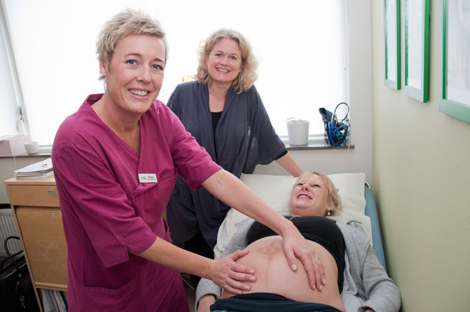 Nurse examining a pregnant woman´s belly