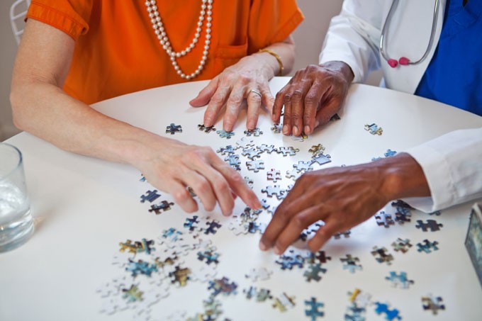 Elder woman and assistant laying a puzzle