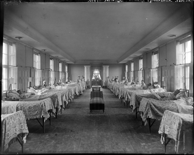 Old picture in b/w, 16 hospital beds in a room 