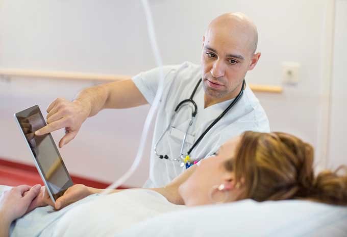 A doctor showing something for his patient on a tablet